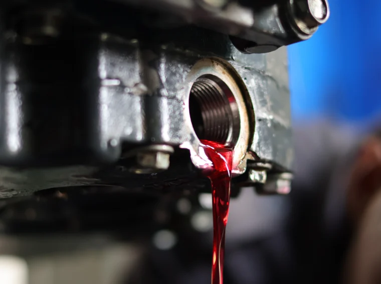Open drain plug with fluid pouring out.